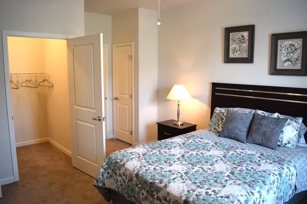 A cozy bedroom with a neatly made bed and a bedside lamp.