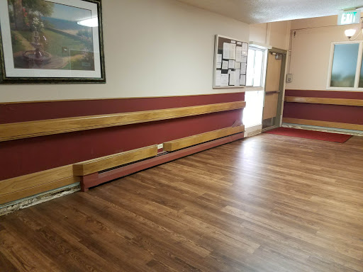 A spacious and well-lit indoor room featuring wooden flooring and decorative wall accents.