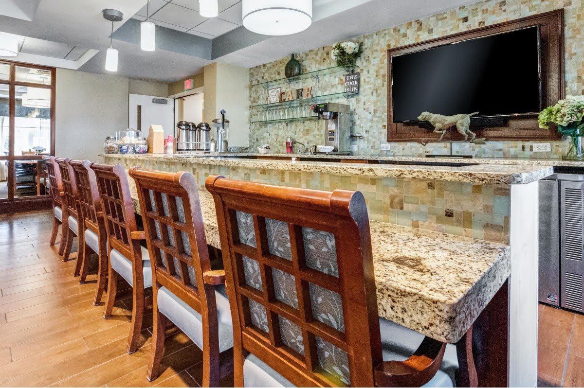 A cozy bar interior featuring a granite countertop and wooden chairs.