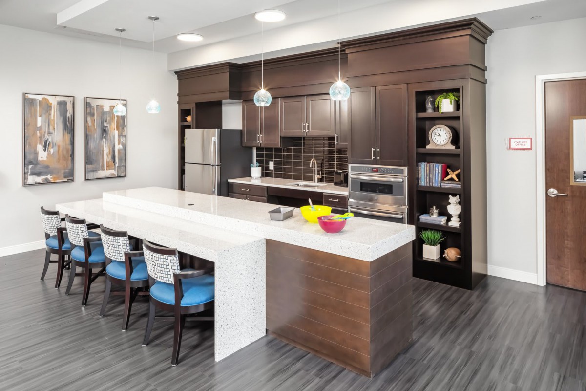 A modern kitchen with dark wood cabinets, a white island, and stainless steel appliances.
