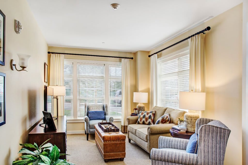 A cozy and well-lit living room with comfortable seating and large windows.