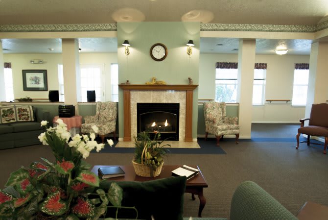 A cozy lounge area with a central fireplace, surrounded by comfortable seating and elegant decor.