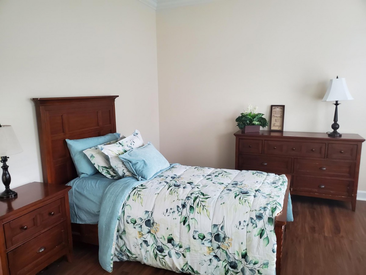 A cozy bedroom with a single bed featuring floral bedding and wooden furniture.