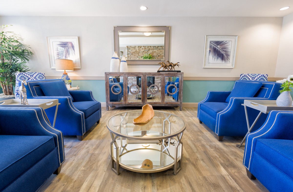 A modern living room with blue chairs, a glass coffee table, and elegant wall decorations.