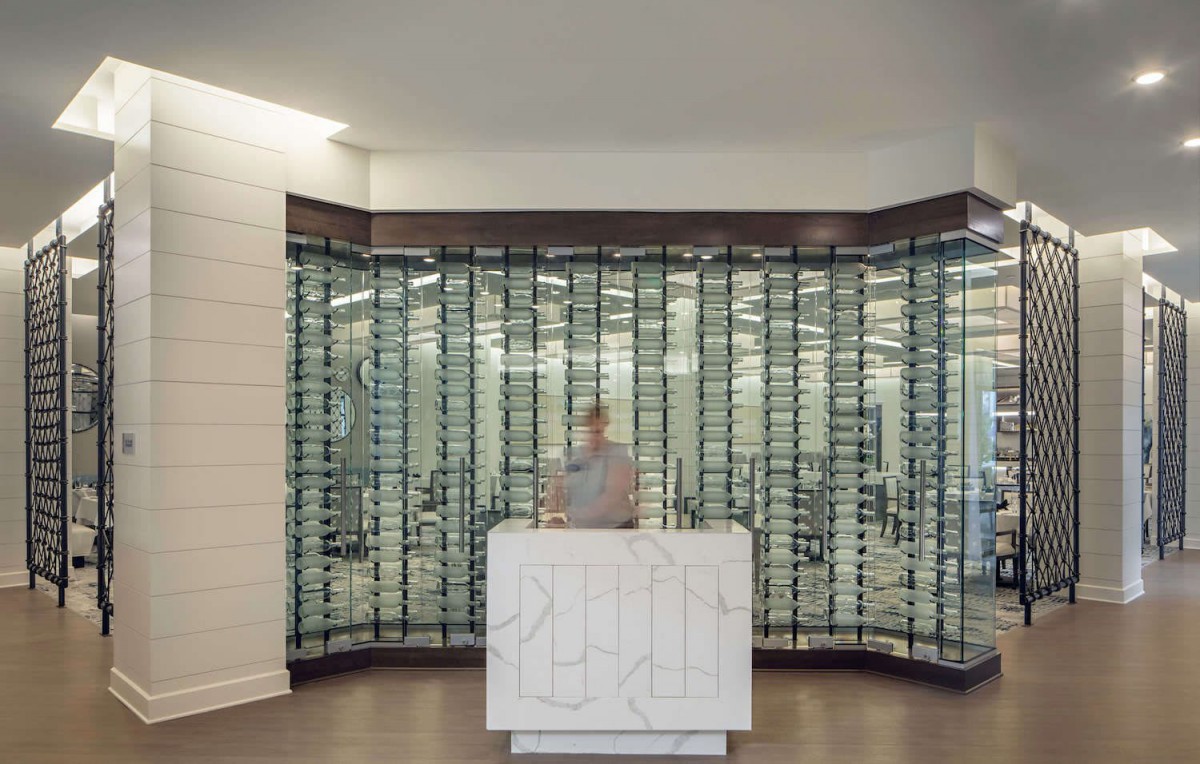 A modern wine cellar with a large selection of bottles displayed behind a reception desk.