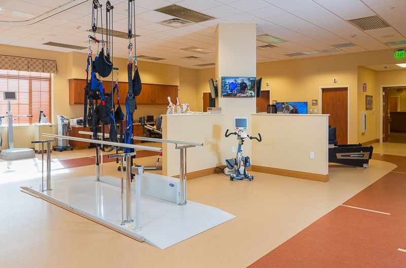 A modern physical therapy room equipped with various rehabilitation devices and exercise machines.