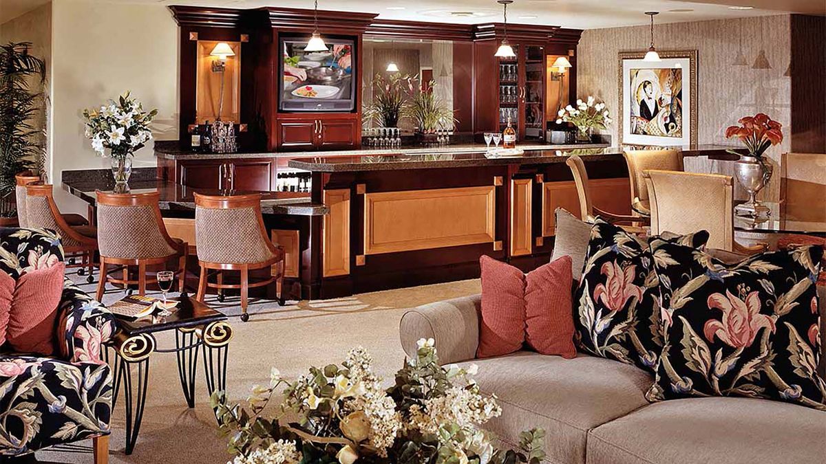 A luxurious living room with a sophisticated home bar, featuring wood paneling and elegant decor.
