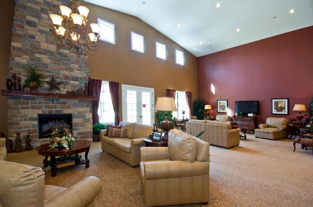 A spacious and elegant living room with a vaulted ceiling, featuring comfortable sofas, a stone fireplace, and a chandelier.