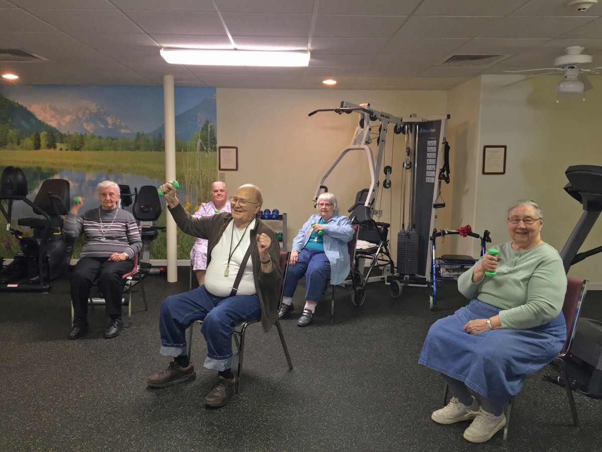Elderly individuals participating in a group exercise session indoors.