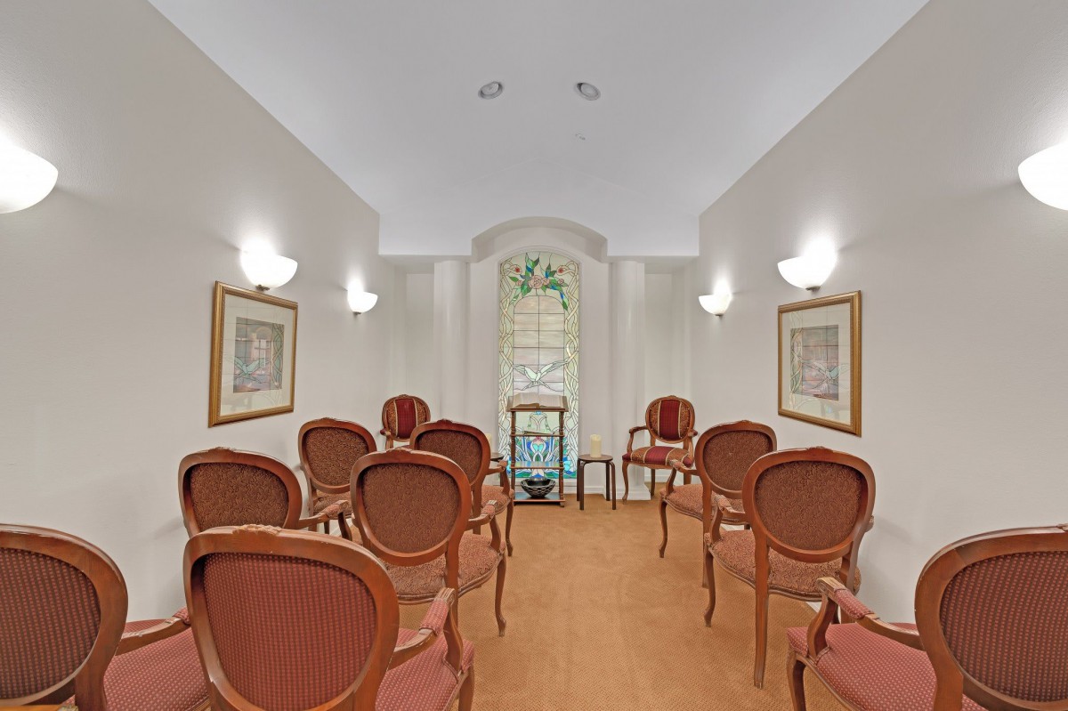 A small, elegantly decorated room with arranged chairs and wall-mounted lights.