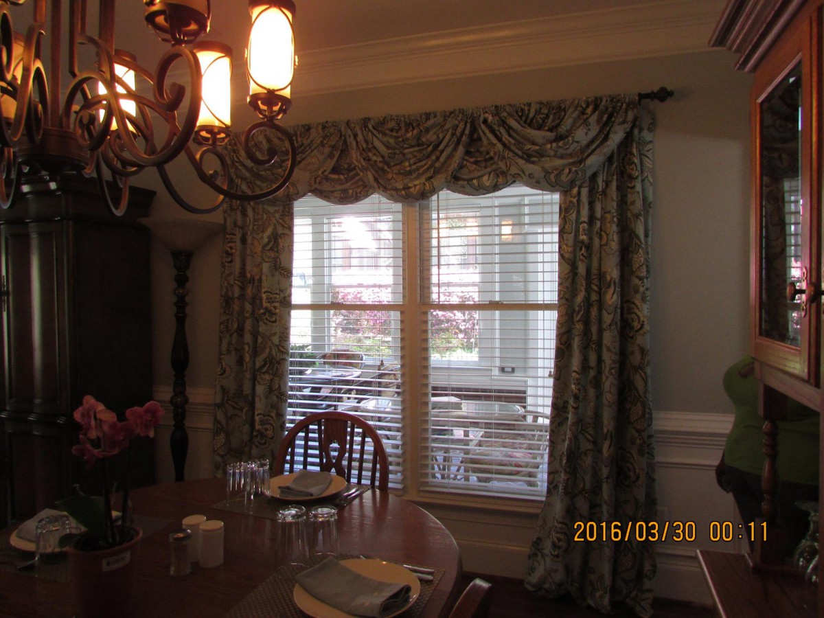 A cozy dining room with elegant curtains and a classic chandelier.