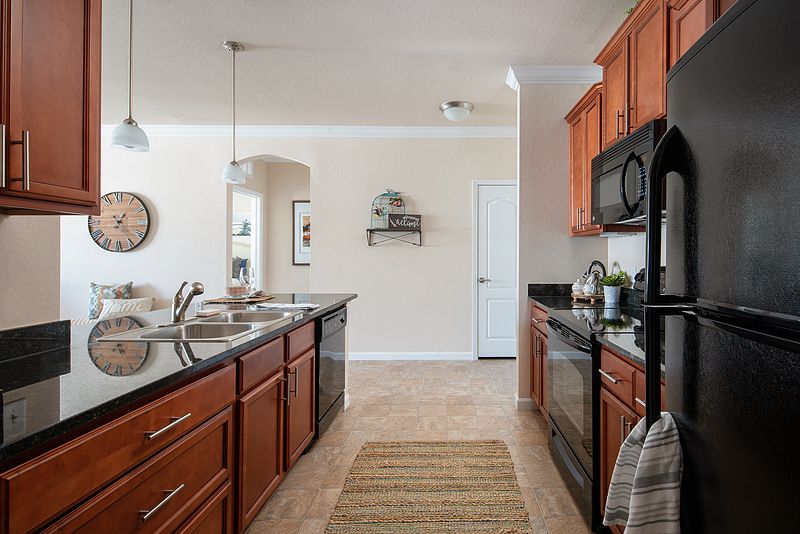 A modern kitchen with wooden cabinets, black appliances, and a sleek countertop.