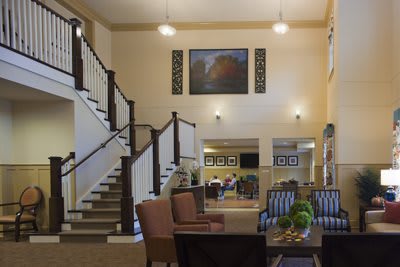 A spacious lobby featuring a staircase, comfortable seating, and elegant decor.