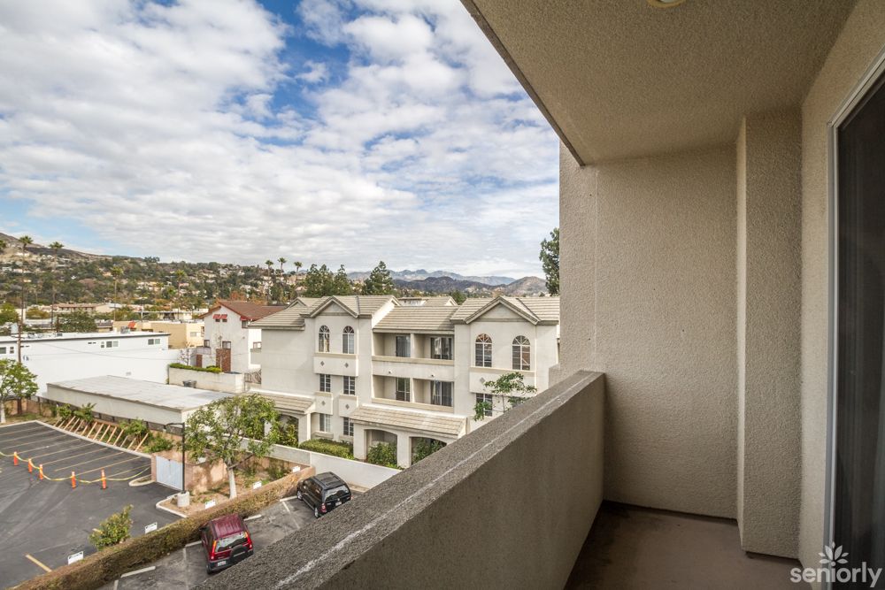 A balcony view overlooking a suburban neighborhood with residential buildings and a cloudy sky.