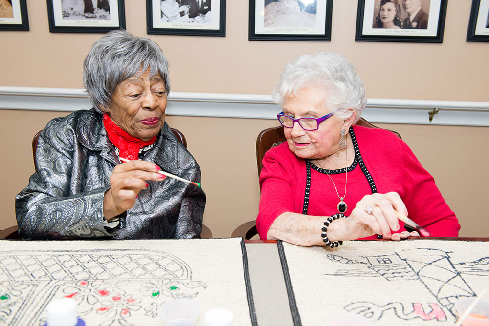 Two elderly women enjoying a crafting activity together.