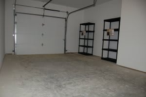 An empty garage with shelves and a concrete floor.