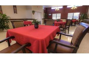 A restaurant dining area with tables covered in red tablecloths and a decorative plant centerpiece.