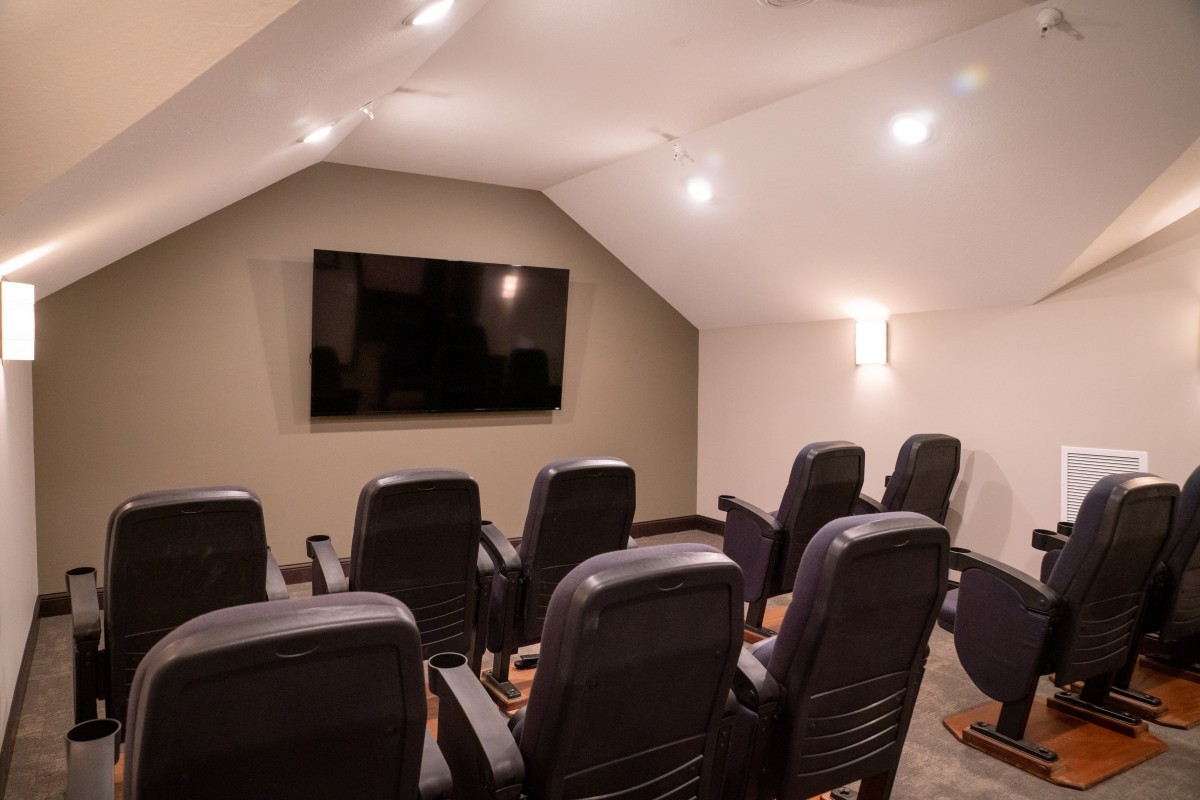 A cozy home theater room with multiple seats facing a large television screen.