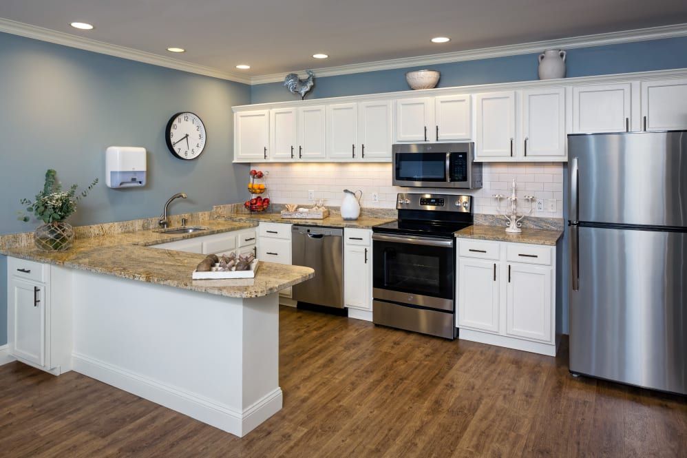 A modern kitchen with white cabinetry, stainless steel appliances, and hardwood flooring.