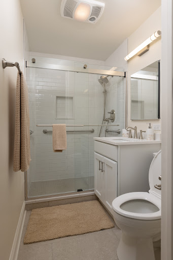 A modern bathroom featuring a glass shower, white cabinetry, and minimalist decor.