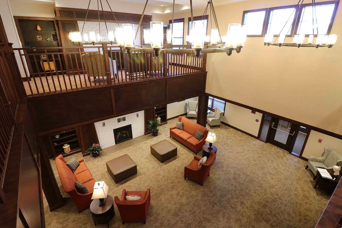 A spacious lounge area with comfortable seating, a grand chandelier, and a cozy fireplace.