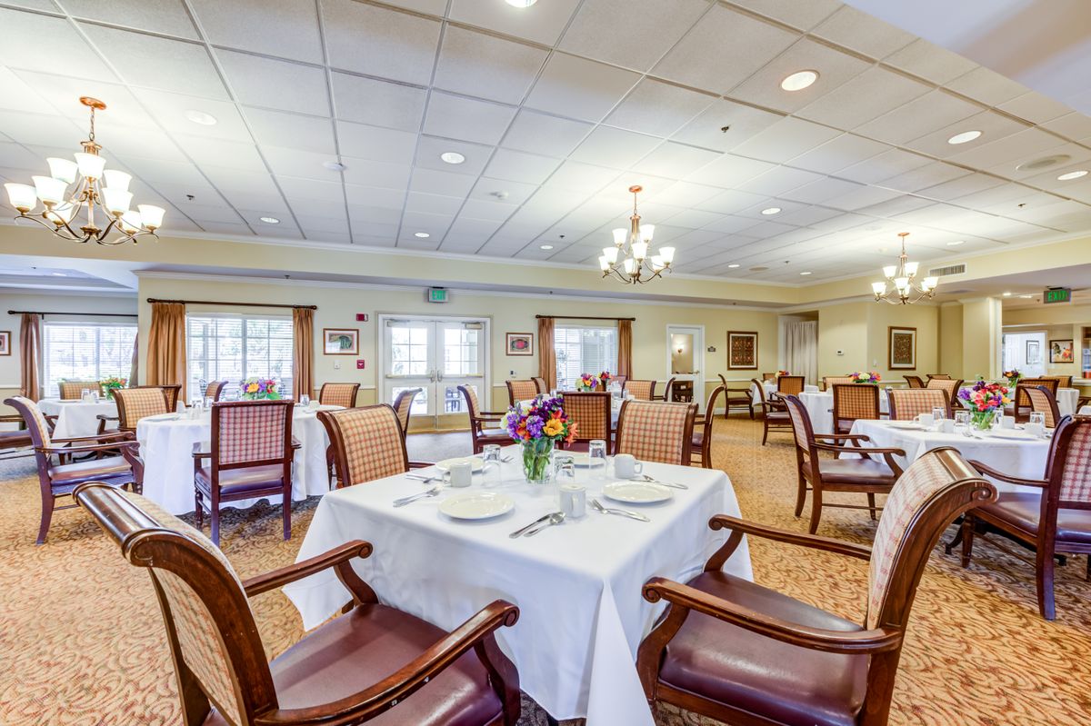 A well-lit dining room with elegantly set tables and comfortable chairs.