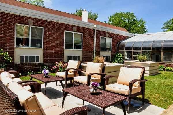 A sunny patio area with comfortable seating and a brick building in the background.
