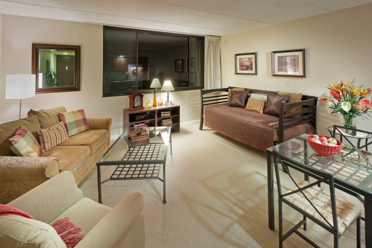 A cozy living room with modern furniture, featuring a sofa, coffee table, and decorative artwork.