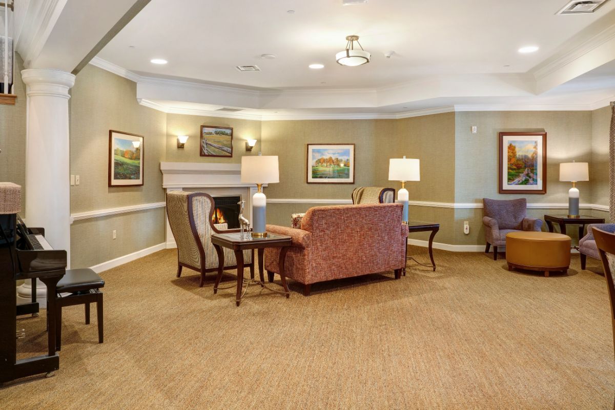 A cozy lounge area with comfortable seating, a fireplace, and decorative paintings on the walls.
