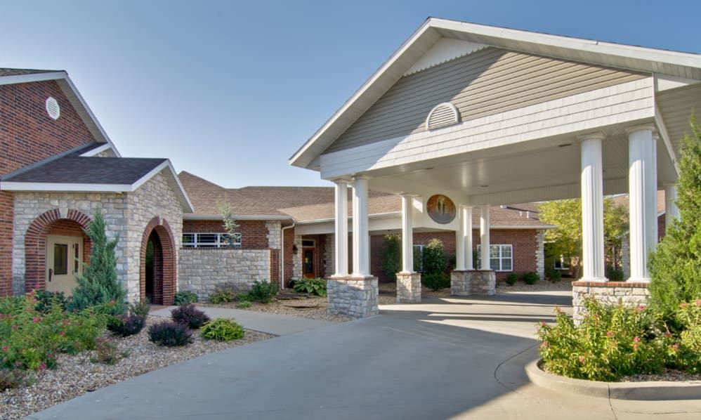 A well-maintained building entrance with a covered driveway and landscaped surroundings.