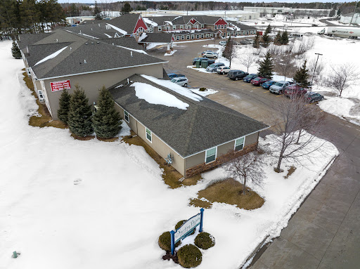 An aerial view of a building surrounded by snow, with a parking lot and trees nearby.