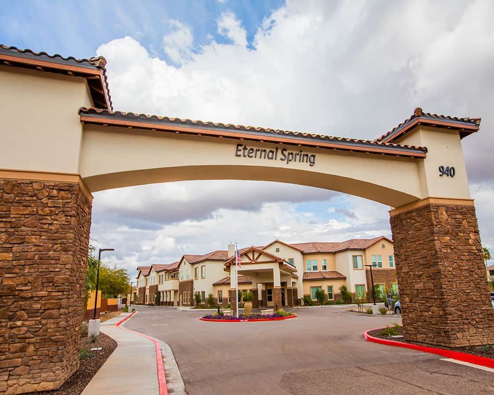 A residential building with a prominent archway entrance under a cloudy sky.