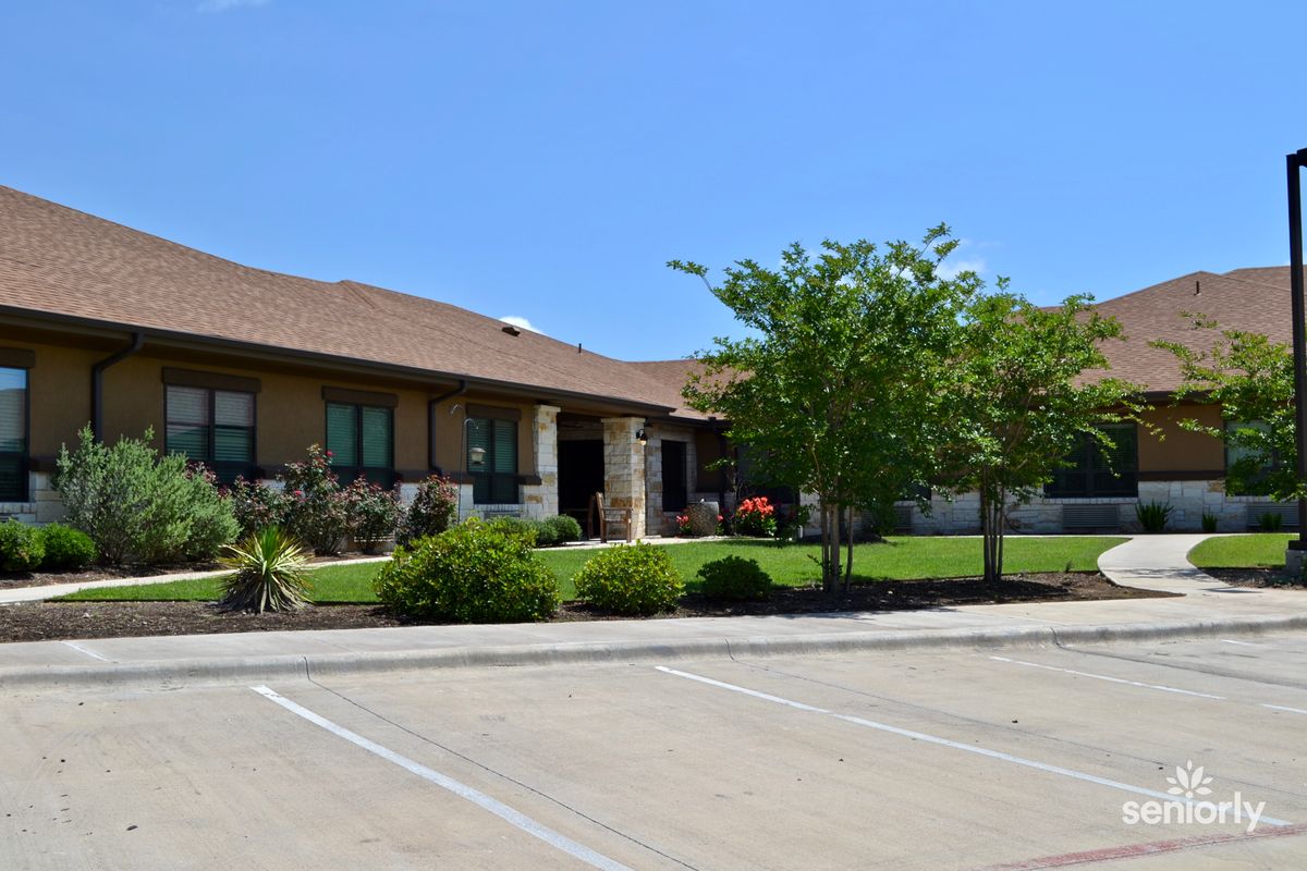 A suburban residential house with a neatly landscaped front yard and an adjacent parking lot.