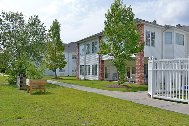 A modern residential building with a well-maintained lawn and surrounding trees.