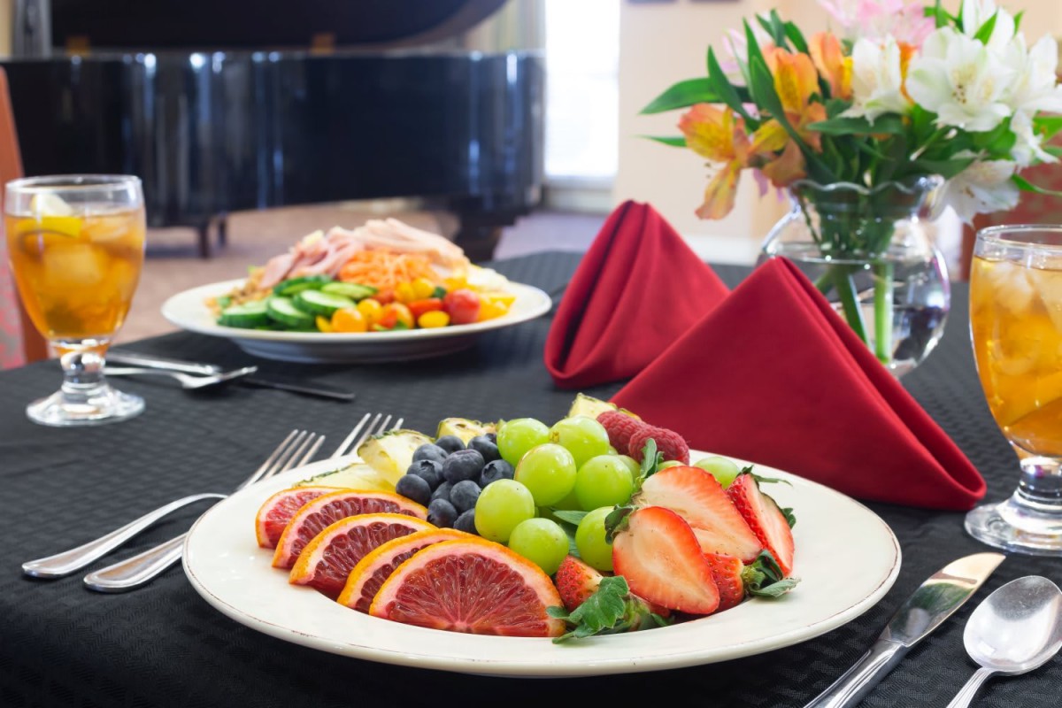 A beautifully arranged fruit platter featuring grapes, strawberries, and oranges on a fine dining table.