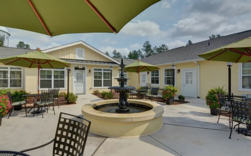 A serene courtyard with a central fountain, surrounded by outdoor seating and patio umbrellas.