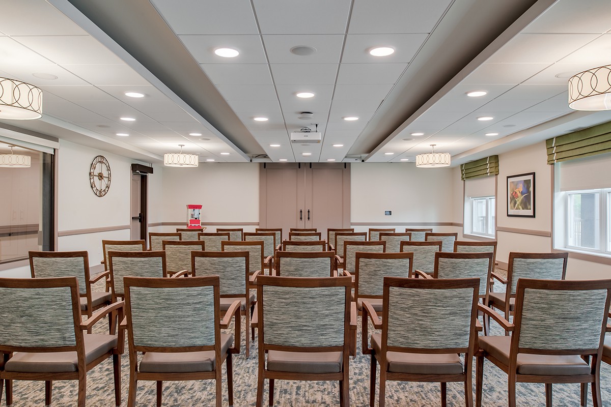 An empty conference room with rows of chairs facing a stage or presentation area.