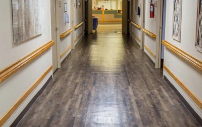 A clean and well-lit hospital corridor with wooden flooring.