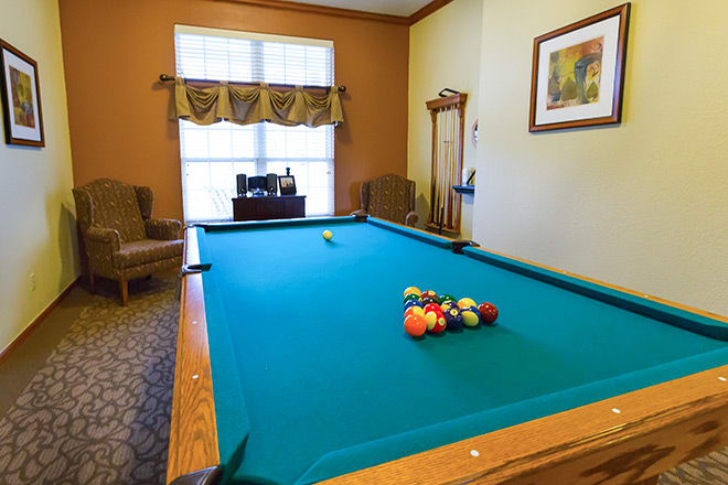 A cozy game room featuring a pool table with billiard balls set up for play.