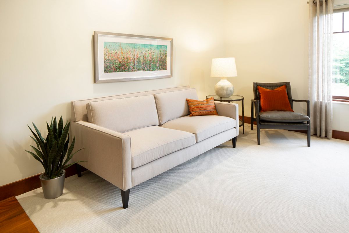 A modern living room with a beige sofa, an armchair, and stylish decor elements.