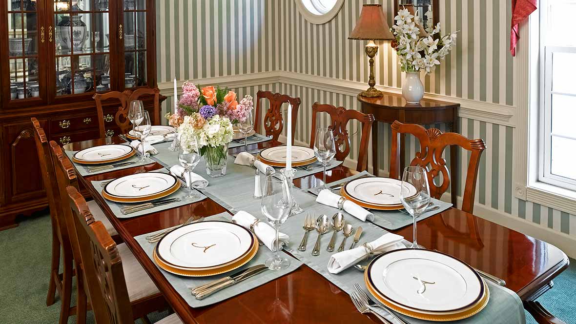 A beautifully set dining table with elegant dinnerware and floral centerpiece.