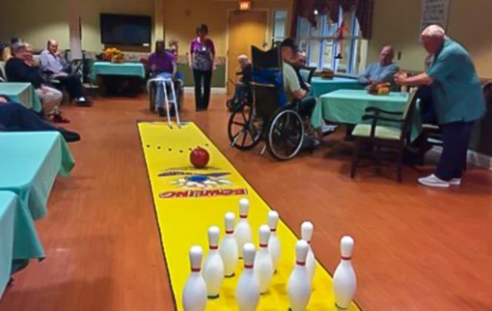 Seniors enjoying a game of indoor bowling in a nursing home.