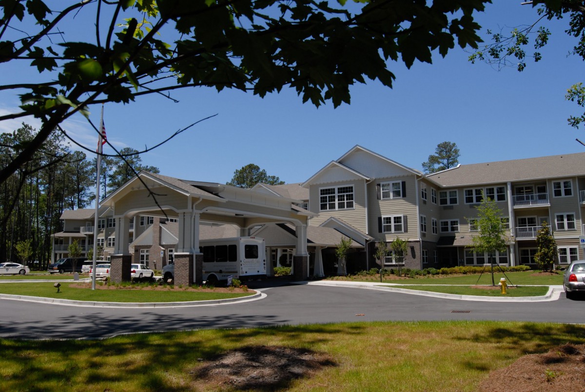 A suburban residential building surrounded by trees under a clear blue sky.