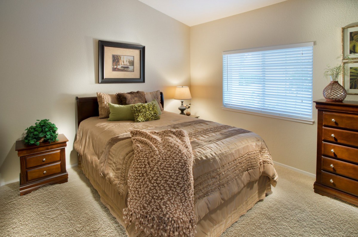 A cozy bedroom with a neatly made bed and warm decor.