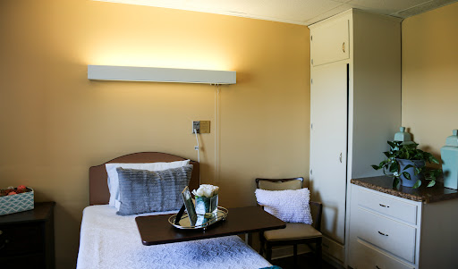 A cozy and well-lit bedroom featuring a bed, side table, and storage unit.