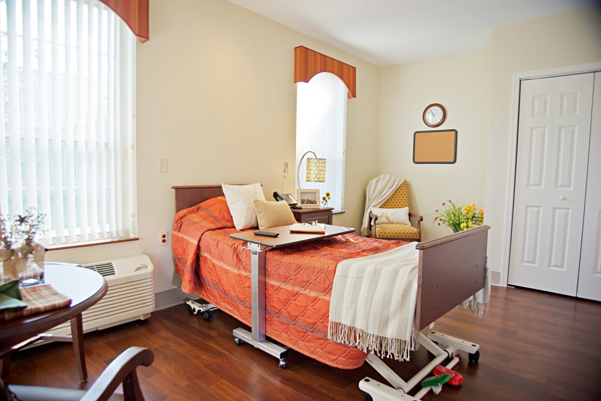 A well-decorated hospital room with an adjustable bed and warm orange accents.
