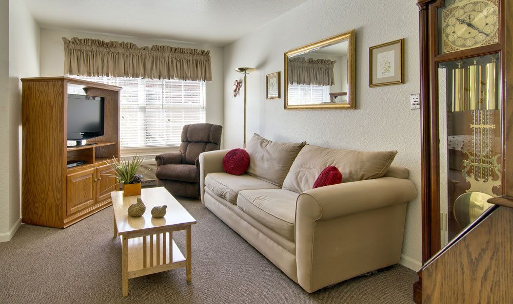 A cozy living room with a beige sofa, armchair, and coffee table adorned with decor.