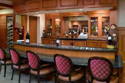 A cozy bar with wooden paneling and upholstered chairs.