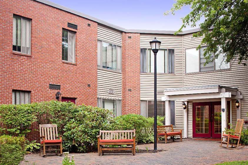 A tranquil courtyard with benches in front of a modern brick and siding building.