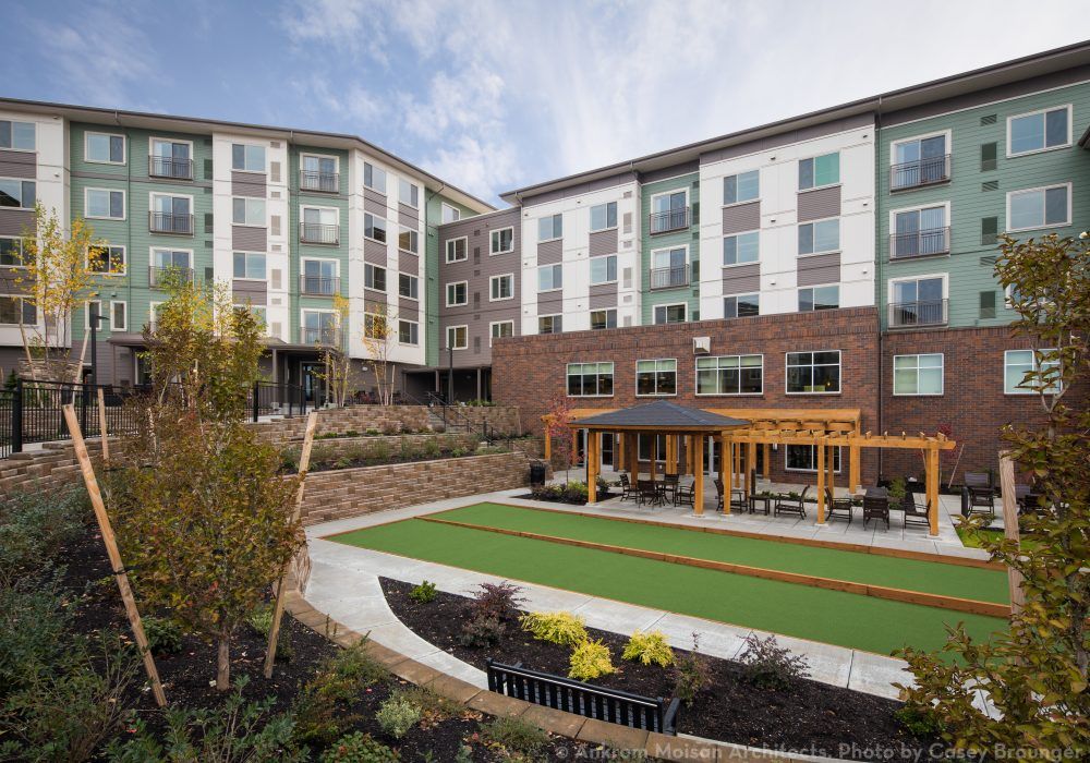 A modern apartment complex with landscaped outdoor areas and a seating area.